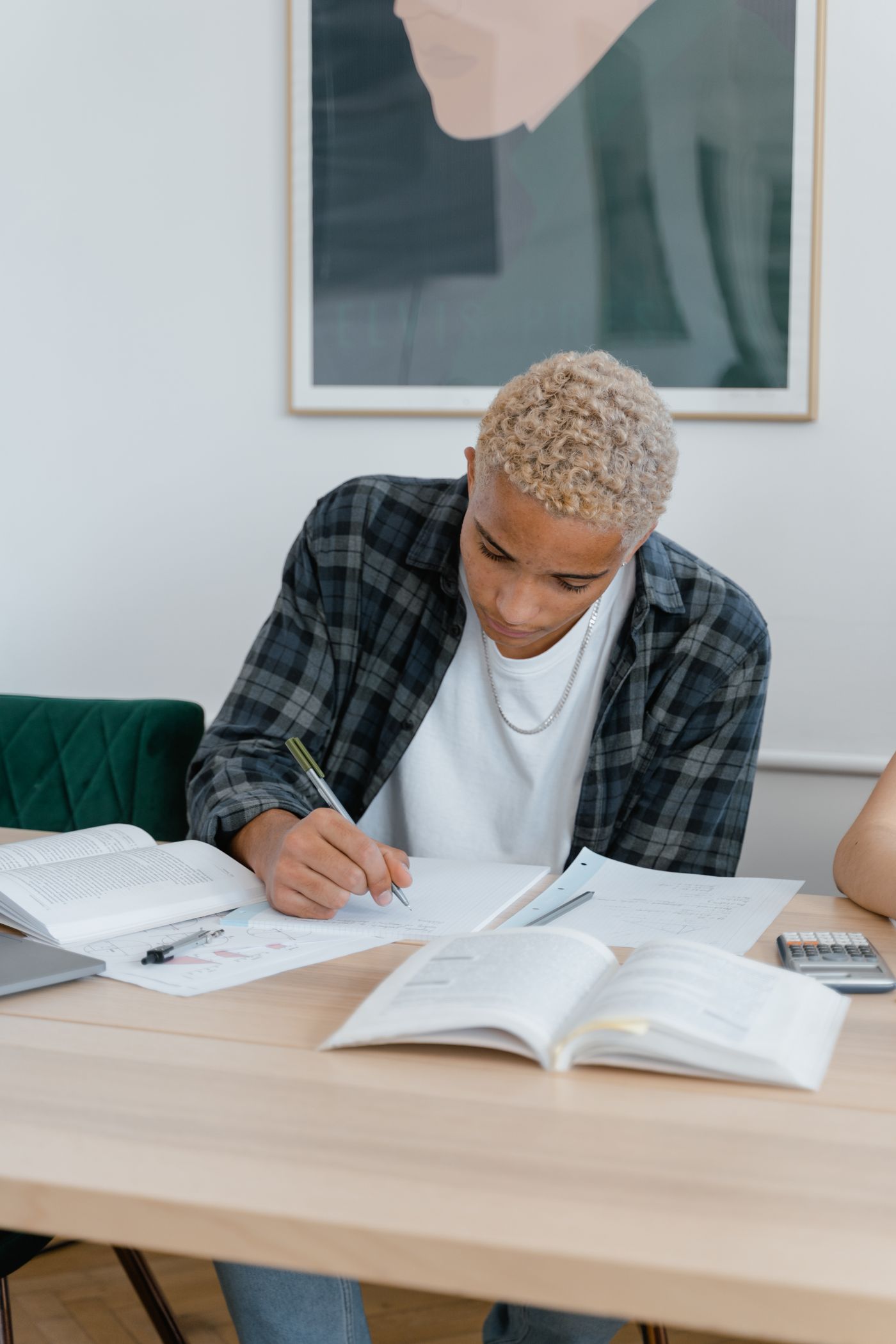 Adolescente estuda com livros e cadernos em uma mesa de casa