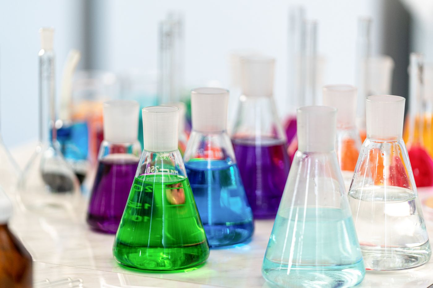 Vidrarias de laboratório com líquidos de diversas cores